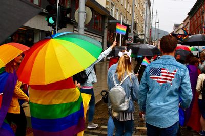 Rear view of people walking on street in rain during pride parade