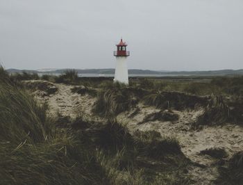 Lighthouse by sea against sky