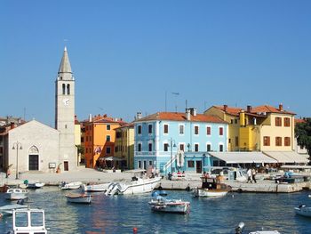 Boats in city against clear blue sky