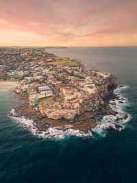 Aerial view of sea and buildings against sky during sunset