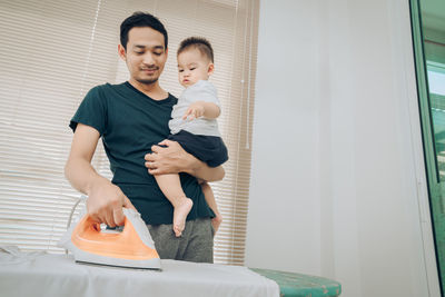 Father and son ironing at home