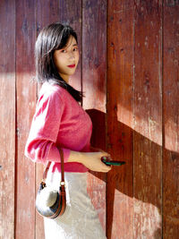 Portrait of young woman standing against wall