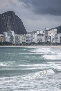 Sea by buildings against sky in city