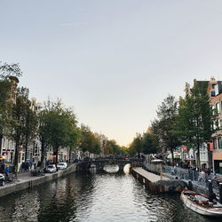 Bridge over canal in city against clear sky