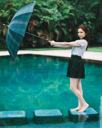 Young woman holding umbrella standing in water