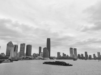 City at waterfront against cloudy sky