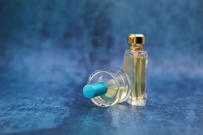 Close-up of small perfume and nail polish bottles on blue table