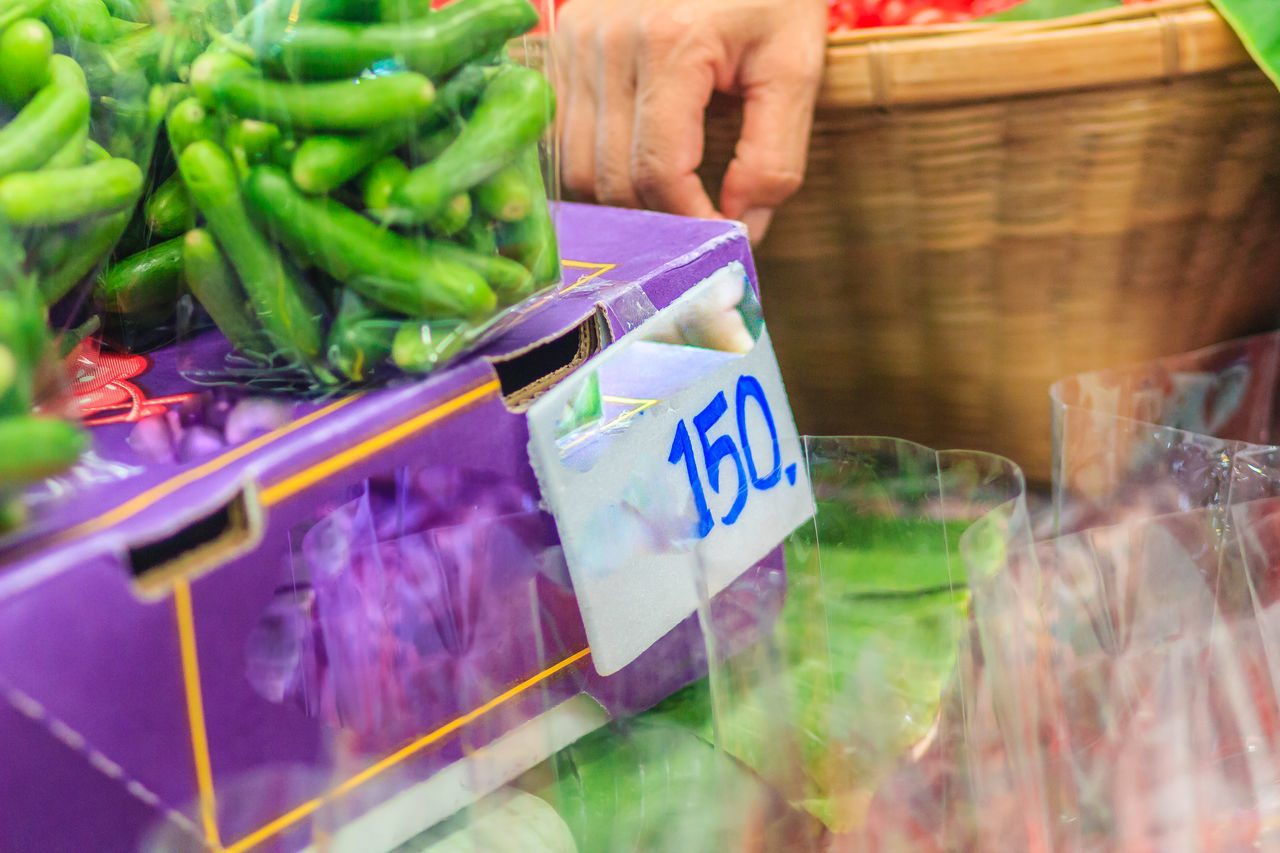 MIDSECTION OF MAN HOLDING VEGETABLES AT MARKET