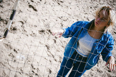 Young woman standing by net