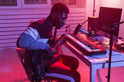 Side view of young man playing guitar