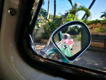 Close-up of side-view mirror against sky