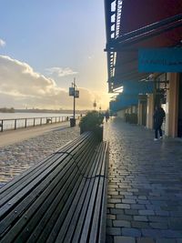 Man walking on footpath against sky in city