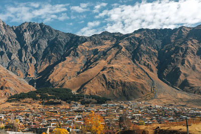 Aerial view of townscape by mountains against sky