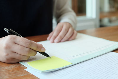 Midsection of businesswoman writing on paper at desk in office