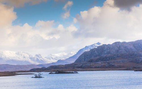 Scenic view of sea and mountains against sky