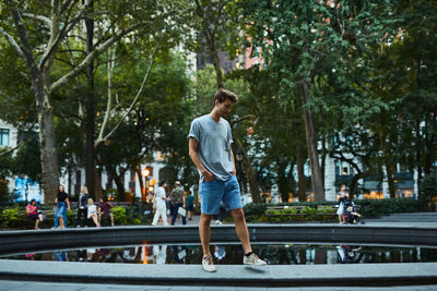 Young man standing by fountain at park