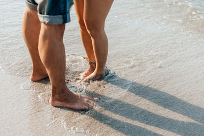 Low section of people walking on beach