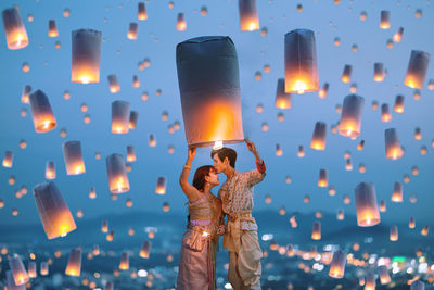 Rear view of woman holding illuminated string lights at night