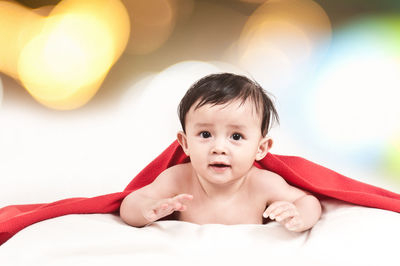 Portrait of cute baby girl lying on bed