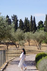 Full length of woman walking against trees