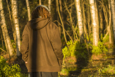 Rear view of woman walking against trees at forest