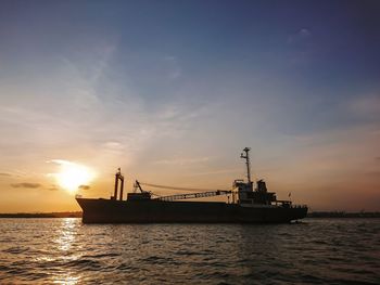 Silhouette ship in sea against sky during sunset