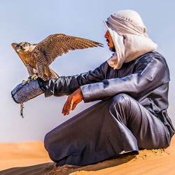 Rear view of man sitting on desert dunes