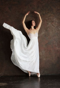 Ballet dancer posing against wall