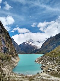 Scenic view of lake by snowcapped mountains against sky