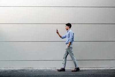 Side view of young man looking away against wall