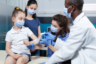 Doctor bandaging girls hand in hospital