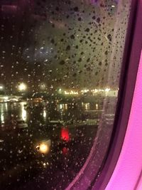 Illuminated road seen through wet window during rainy season