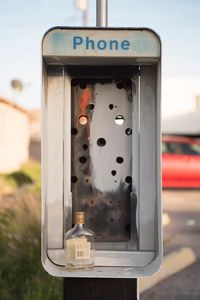 Close-up of glass bottle on abandoned telephone booth