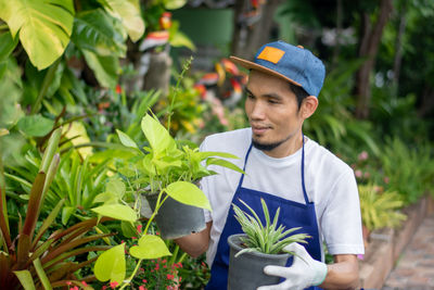 Young man smiling while standing by plants