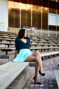 Full length of young woman relaxing on bleacher at amphitheater