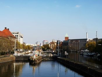 Bridge over river by buildings in city against sky