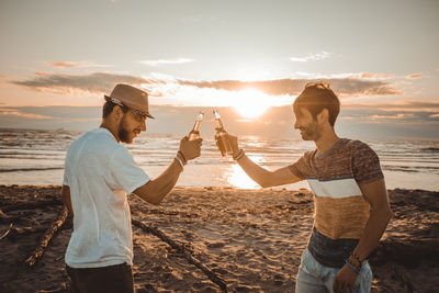 Full length of young man photographing sea at sunset