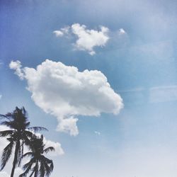 Low angle view of trees against cloudy sky