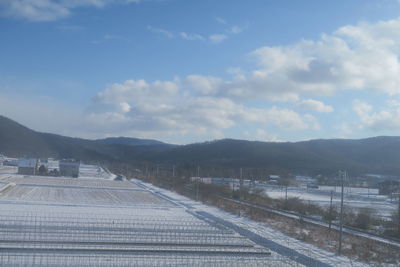 Railroad tracks on field by mountains against sky