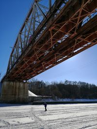 Man walking on snow covered bridge in winter