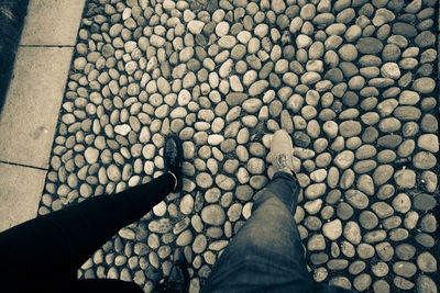 Low section of man standing on pebbles