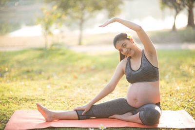 Portrait of pregnant woman doing yoga on field