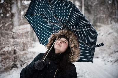 Woman with umbrella on snow covered field