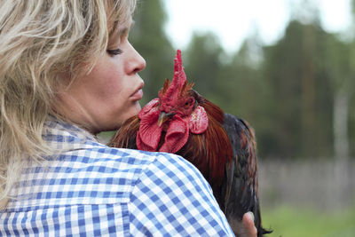 Beautiful woman in the farm holding a chicken, healthy lifestyle