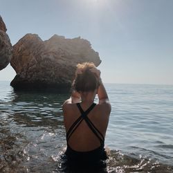 Rear view of woman standing in sea against sky