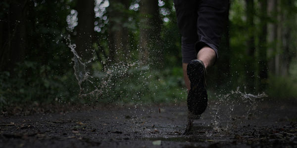 Low section of man running outdoors during rainy season