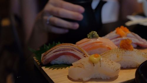 Cropped image of woman reaching towards sushi