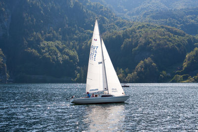 Sailboat sailing on sea against mountain