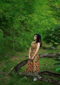 Young woman standing against tree trunk