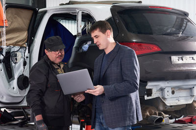 Man standing with mechanic in garage